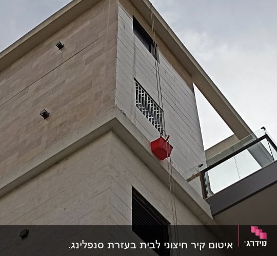 דלי אדום תלוי על חבל ליד בניין